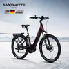 A burgundy electric bicycle is displayed against a snowy mountain backdrop with a bright sun flare. Produktbild-Vorschau