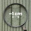 A close-up view of a textured fabric, likely a pillow cover, magnified by a lens. Text indicates a measurement of approximately 1 cm. Produktbild-Vorschau