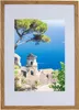 A framed picture of a coastal view with a building and a tree. Produktbild-Vorschau