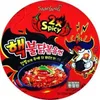 The image shows the lid of a Samyang Buldak Ramyun 2x spicy instant noodle cup. It features bold graphics, including cartoon chili peppers, a stylized chicken character holding a bomb, and the product name in Korean and English. Produktbild-Vorschau