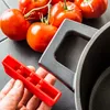 A hand holds a red accessory next to a pot handle and tomatoes. Podgląd zdjęcia produktu