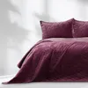 A close-up view of a quilted bedspread and pillows on a bed. Produktbild-Vorschau