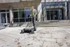A man is using a Kärcher KM 70/20 C 2SB sweeper on a paved outdoor area in front of a modern building. Voir les images du produit