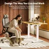 A woman is sitting in an office chair and playing with a cat in front of a standing desk. Produktbild-Vorschau