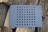 A rectangular cast iron grate with many holes is placed on a pile of firewood. Produktbild-Vorschau