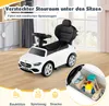 A white ride-on car with a black seat and steering wheel, placed on a wooden floor. The background shows a blurred interior with cabinets and a window. A circular inset shows the car's storage compartment filled with wooden toys. Produktbild-Vorschau