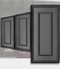 Three dark gray decorative wall panels with a raised frame design, arranged diagonally. The background shows a gray textured wall and a hint of furniture. The foreground is a white surface. Náhled obrázku produktu