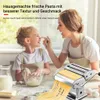 A woman and a child are making pasta at a kitchen counter. Produktbild-Vorschau
