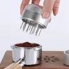 A hand is holding a coffee distributor tool over a portafilter filled with coffee grounds. Náhľad obrázku produktu