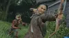 A person is aiming a bow and arrow at an unseen target, while a zombie-like creature approaches from the left. Produktbild-Vorschau