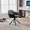 A dark gray swivel chair with armrests is placed on a rug in a room with a desk and a window. Produktbild-Vorschau