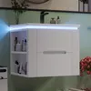 A modern white bathroom vanity with LED lighting and open shelving, mounted on a light green tiled wall. Produktbild-Vorschau