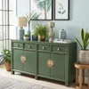 A green sideboard with decorative items on top, placed in a room with light blue walls and a window. Voir les images du produit