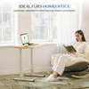 A woman reading a book in a rocking chair next to a height-adjustable desk with a laptop. Voir les images du produit