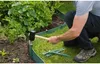 A person is installing green garden edging into the ground next to a bush. Produktbild-Vorschau
