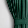 A close-up view of a dark green velvet curtain with pleats and a fabric band. Produktbild-Vorschau