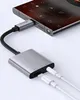 A close-up shot of a USB-C to 3.5mm audio adapter connected to a smartphone, with two white USB-C cables plugged into the adapter. Náhľad obrázku produktu
