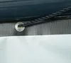 A close-up view of a grommet and rope on a green tarp. Podgląd zdjęcia produktu