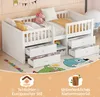 A white wooden children's bed with drawers, shown with pillows and a stuffed unicorn. The bed is on a colorful rug with cartoon characters. Anteprima dell’immagine prodotto