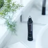 A nose hair trimmer sits on a white countertop next to a plant. Podgląd zdjęcia produktu