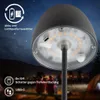 A close-up of the bottom of a lamp with text overlays, set against a night sky and blurred background of people camping. Anteprima dell’immagine prodotto