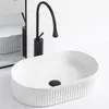 A white oval countertop sink with a black faucet and a reflection in a mirror. Podgląd zdjęcia produktu