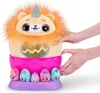A plush toy lion with a unicorn horn sits in a pink egg-shaped holder, surrounded by smaller toy eggs. Hands are shown interacting with the toy. Náhled obrázku produktu