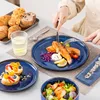 A table setting with a meal, including salmon, salad, and pastries, with a person eating. Produktbild-Vorschau