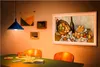 A dining room scene with a table set for a meal and a large framed television displaying artwork on the wall. Voir les images du produit