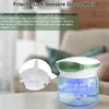 A water-based air purifier is shown on a table in a living room setting, with a close-up inset of its internal component. Produktbild-Vorschau