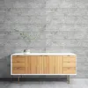 A modern sideboard with wooden drawers and doors against a textured concrete wall. Produktbild-Vorschau