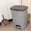 A gray pedal trash can and a gray dustpan with an orange brush are placed on a tiled floor next to a white cabinet. Náhled obrázku produktu