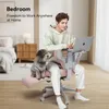A man is working on his laptop while sitting in a pink office chair with a dog on his lap. The scene is set in a bedroom. Podgląd zdjęcia produktu