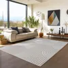 A modern living room with a large window, sofa, plants, and a rug. Voir les images du produit