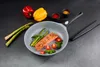 A frying pan with salmon, asparagus, and cherry tomatoes, along with bell peppers and spices, arranged on a dark surface. Produktbild-Vorschau