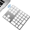 A silver wireless numeric keypad is shown at an angle on a white background, next to a portion of a laptop. Náhled obrázku produktu