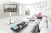 A modern living room with a woman relaxing on a sofa, a coffee table, and a TV on a stand. Anteprima dell’immagine prodotto