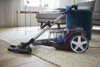 A vacuum cleaner is placed on a rug in a living room setting. Produktbild-Vorschau