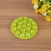A green suction mat with multiple suction cups is placed on a wooden surface, with a bouquet of yellow and white flowers in the upper right corner. Anteprima dell’immagine prodotto