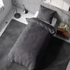 A neatly made bed with dark gray striped bedding in a minimalist room. Produktbild-Vorschau