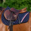 A close-up of a brown leather saddle on a navy blue quilted saddle pad with red and white stripes and the Tommy Hilfiger logo, placed on the back of a brown horse. Produktbild-Vorschau
