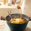 A person is basting a whole chicken in a pot of broth with a wooden spoon, while a digital thermometer is inserted into the chicken. Produktbild-Vorschau