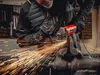 A person is using an angle grinder to cut metal, creating a shower of sparks. Podgląd zdjęcia produktu