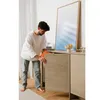 A man is opening a cabinet door of a wooden sideboard in a modern room. Produktbild-Vorschau