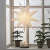 A paper star lantern hangs in a window with small Christmas trees and candles on the windowsill. Podgląd zdjęcia produktu