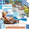 A woman relaxing on a lounge chair on a balcony with a view of the sea, surrounded by decorative tiles and mosaic tables with plants. Produktbild-Vorschau