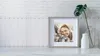 A framed picture of two smiling women is displayed on a shelf, next to a vase with a plant. Produktbild-Vorschau