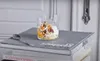 A glass of yogurt parfait with granola and fruit sits on top of a stack of books, with a spoon to the left. Náhľad obrázku produktu