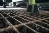 A close-up shot of a black foot attachment on a metal grate, with a green ladder leg visible. Podgląd zdjęcia produktu