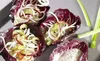 Radicchio cups filled with shredded vegetables and a creamy dressing, with celery stalks in the background. Produktbild-Vorschau